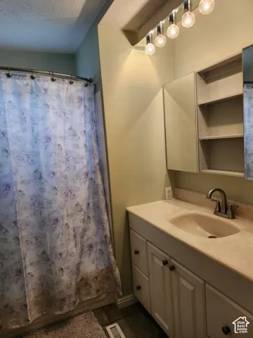 Bathroom vanity featuring stone-finish countertop, integrated sink, shaker-style cabinetry, and built-in recessed shelving
