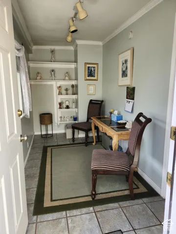 Neutral-toned interior room featuring tile flooring, built-in recessed shelving, crown molding, and adjustable track lighting