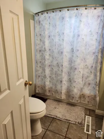 Bathroom featuring a tub-shower combination with a curved shower rod and square ceramic floor tiling
