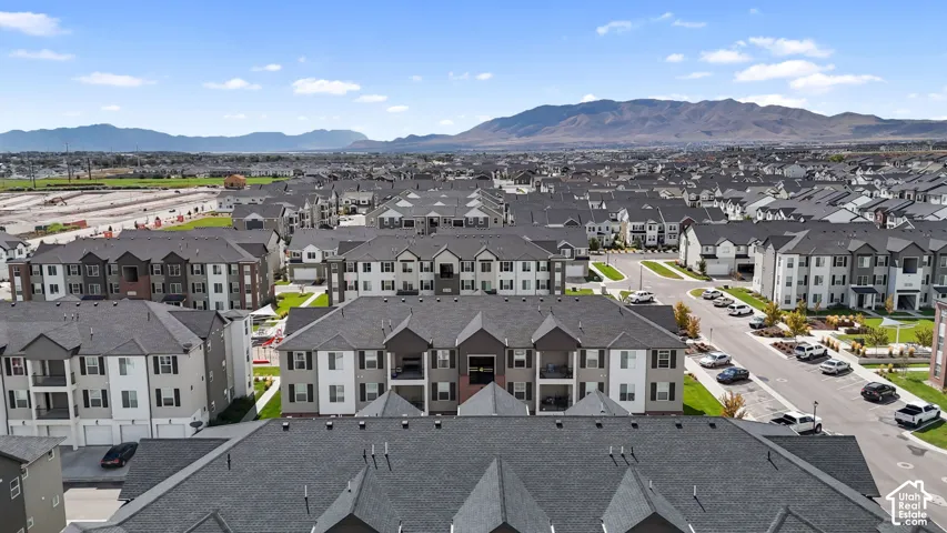 Aerial perspective of residential multi-story buildings featuring gabled rooflines, neutral-toned siding, integrated private balconies, and mountain scenery