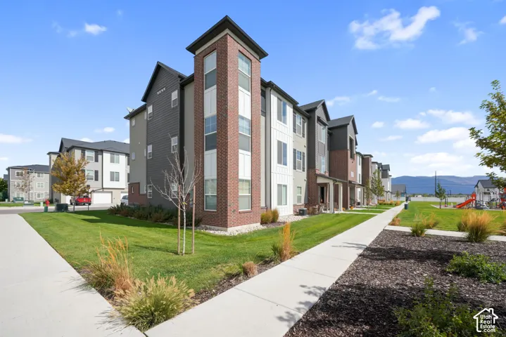 Multi-story exterior featuring a combination of brick masonry and board-and-batten siding, complemented by concrete walkways, manicured landscaping, and mountain scenery