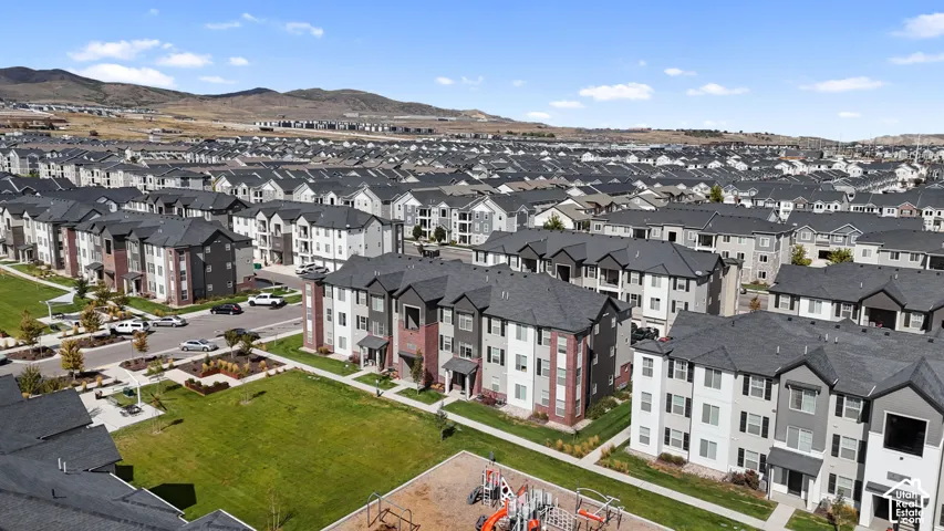 Aerial perspective of multi-story residential structures featuring brick and neutral-toned exteriors, pitched roofs, and dedicated playground areas