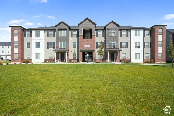 Multi-story exterior featuring a brick and panel facade, gabled rooflines, and a paved walkway bordering a lawn