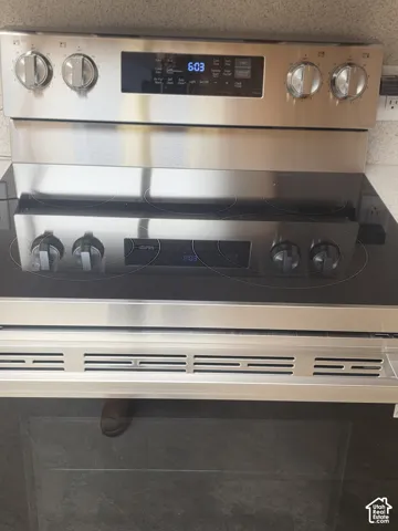 Stainless steel electric range featuring a flat glass cooktop, front-facing control knobs, a digital display panel, and an integrated oven