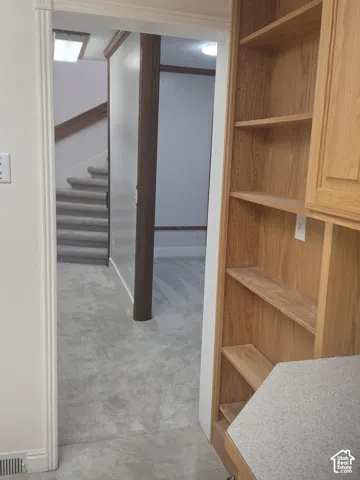 Built-in wood shelving unit, carpeted flooring, staircase with wood handrail, and trim work