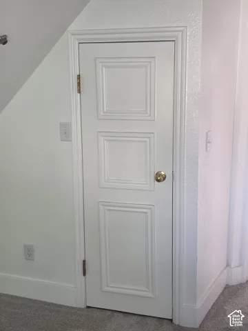 Under-stair storage featuring a white-painted, three-panel door with brass-finish hardware and detailed trim work