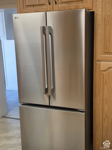 Stainless steel French-door refrigerator featuring an integrated bottom-freezer drawer, complemented by oak cabinetry with arched panel detailing