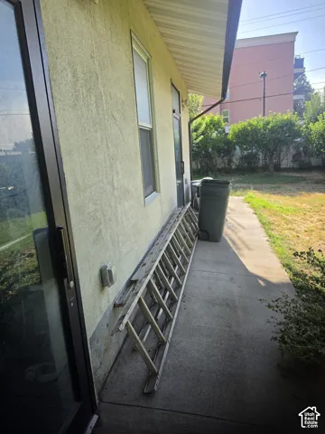Stucco exterior siding, concrete patio, sliding glass door, and exterior window