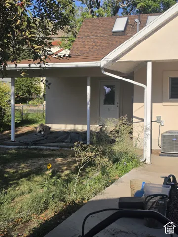 Stucco exterior featuring a covered patio, shingled roof, and dual roof-mounted skylights