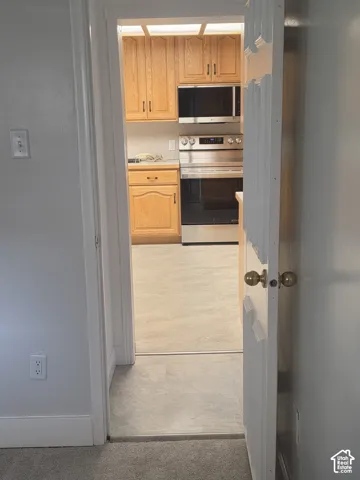 Kitchen featuring wood cabinetry, stainless steel microwave, stainless steel range, and solid-surface flooring