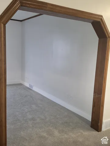 Architectural arched doorway featuring natural wood trim and neutral carpeting