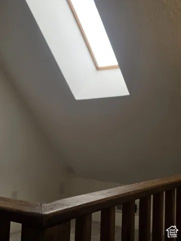 Sloped ceiling featuring a rectangular skylight and wood-finish railing