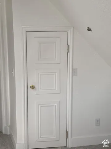 White three-panel door with brass-finish hardware, enclosed within a sloped architectural ceiling line
