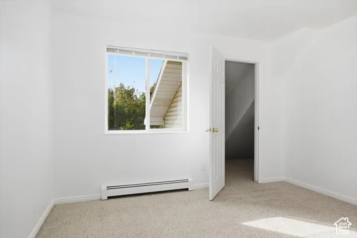 Neutral wall paint, carpeting, and a sliding window with horizontal blinds