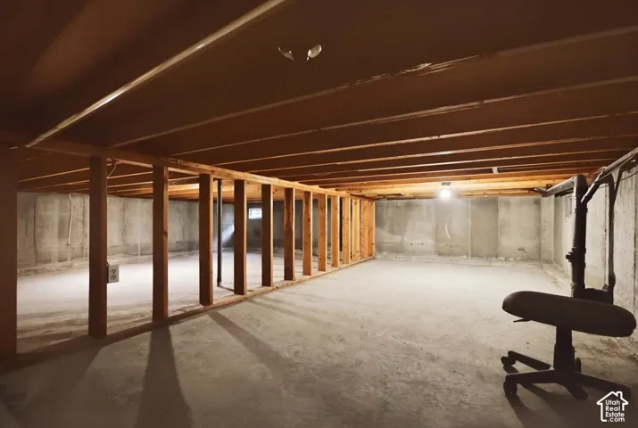 Unfinished lower level featuring exposed wood joists, concrete foundation walls, and concrete flooring