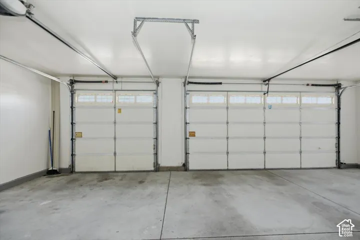 Three-car garage featuring finished walls, concrete flooring, and dual overhead doors with upper-panel glazing