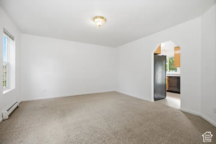 Neutral-toned carpeted flooring, white walls, and a distinctive arched doorway