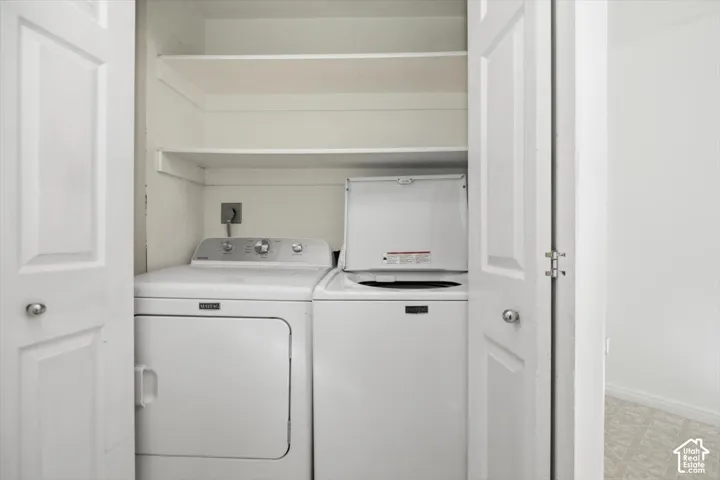 Laundry closet featuring white bi-fold doors and two integrated upper storage shelves