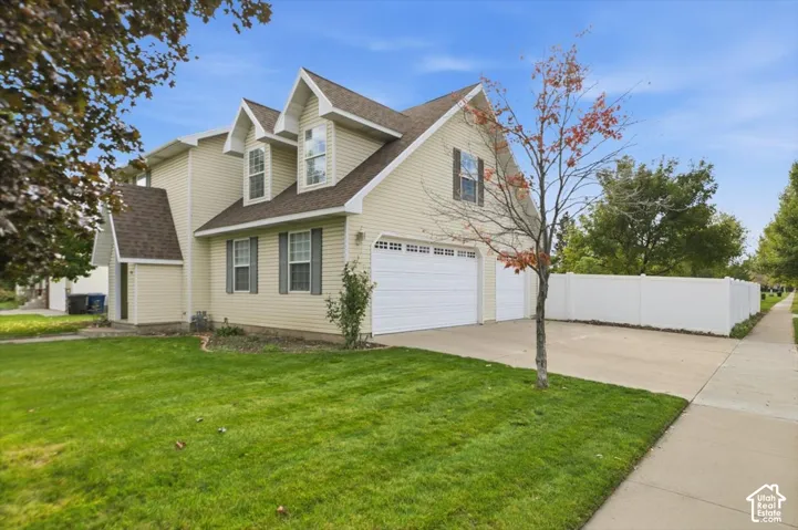 Two-story exterior featuring light-toned horizontal siding, multiple roof gables, a three-car garage, and perimeter white vinyl fencing