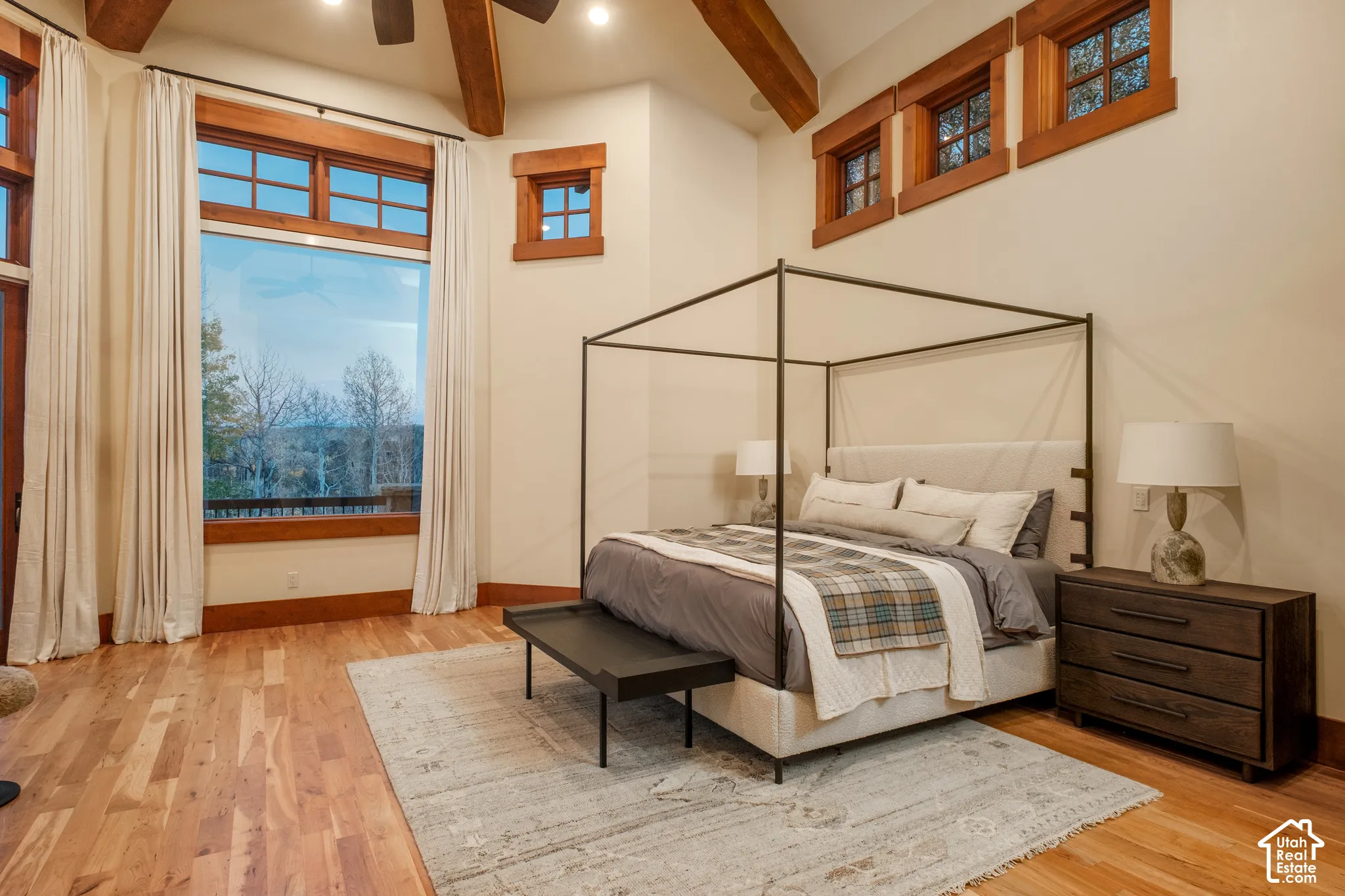 Vaulted ceilings with exposed timber beams, wood-finish flooring, and expansive windows framed in natural wood