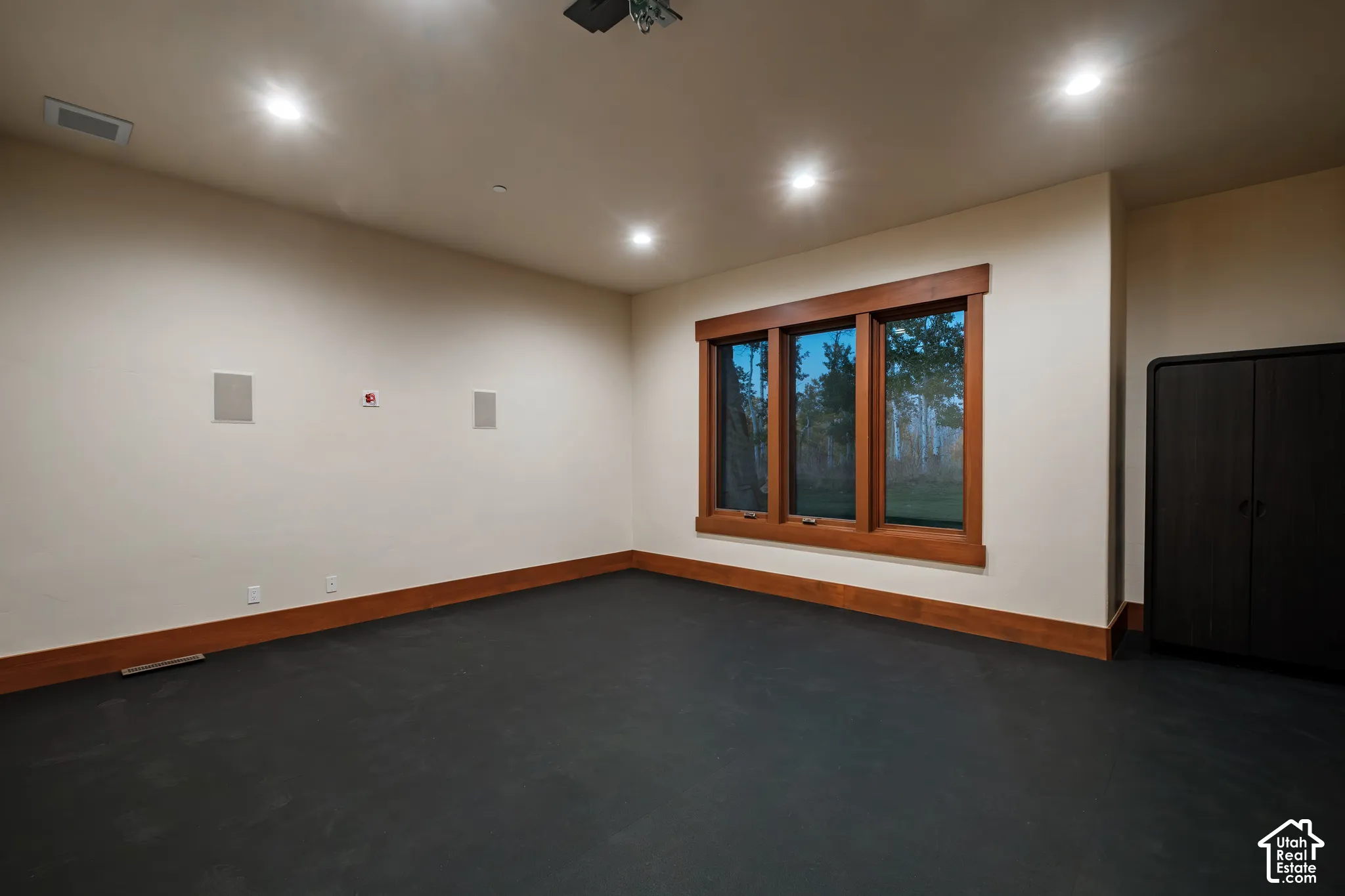 Interior room featuring recessed ceiling lighting, dark flooring, wood-framed windows, and built-in cabinetry