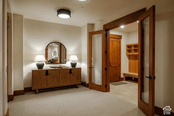 Wood-framed glass panel doors, recessed ceiling lighting, light-toned carpeting, and tiled entry flooring featuring built-in wood shelving and bench seating