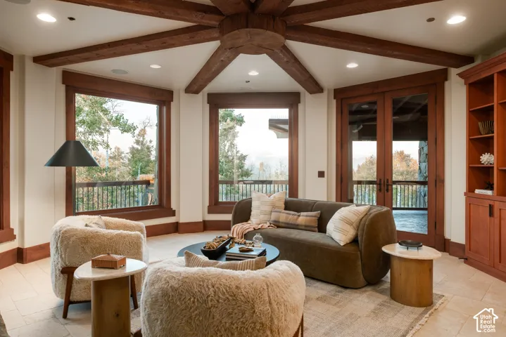 Hexagonal room featuring vaulted ceilings with exposed wood beams, large windows with natural wood trim, built-in floor-to-ceiling cabinetry, recessed lighting, and tile flooring