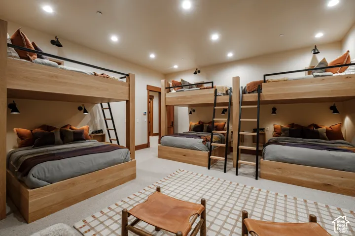 Custom wood-frame bunk beds with integrated ladders, recessed ceiling lighting, and matte black wall-mounted reading sconces