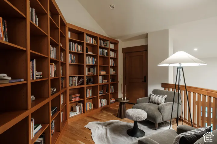 Custom floor-to-ceiling wooden shelving, solid wood door with matching trim, wood-finish flooring, and sloped ceiling with recessed lighting