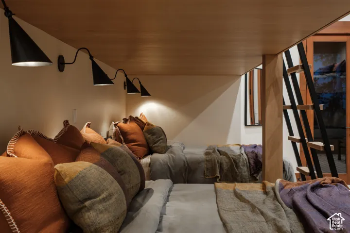 Built-in bunk structure with wood-finish ceiling, metal ladder, and three wall-mounted black cone sconces