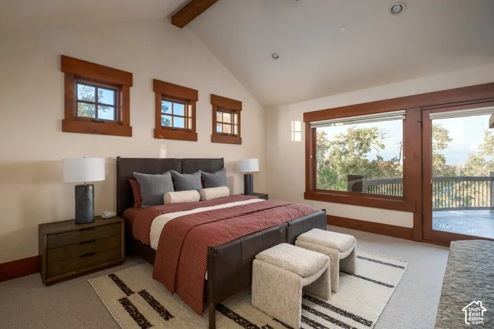 Vaulted ceiling featuring an exposed wood beam, natural wood-trimmed windows, recessed lighting, and a glass-paned door opening to an exterior balcony