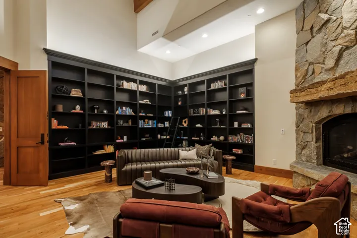 Floor-to-ceiling built-in shelving, natural stone fireplace with a substantial timber mantel, vaulted ceiling, and wood-finish flooring