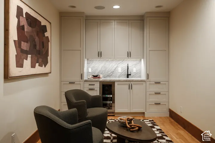 Custom built-in cabinetry featuring shaker-style doors, stone-finish backsplash, under-cabinet lighting, integrated beverage refrigerator, and matte black hardware