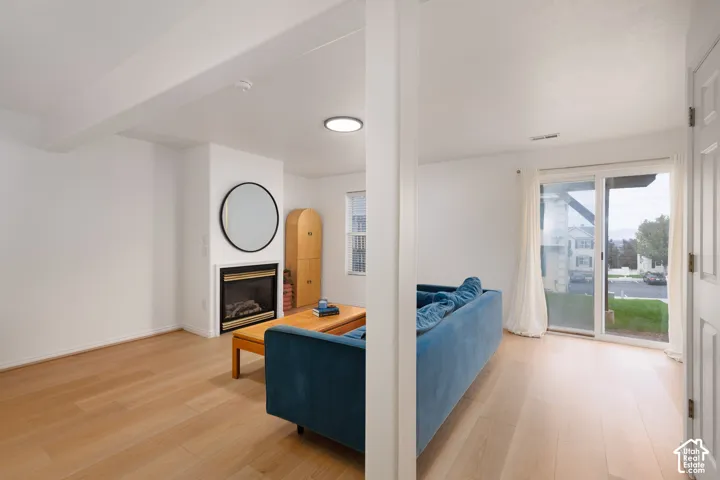 Living area featuring light wood-finish flooring, a fireplace with a black surround, flush-mount lighting, and sliding glass doors