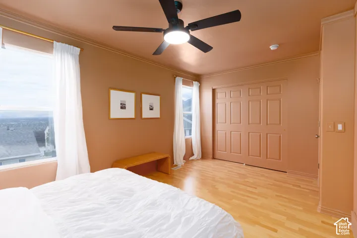 Room featuring wood-finish flooring, dual windows with exterior mountain scenery, ceiling fan with integrated lighting, and multi-panel bi-fold closet doors