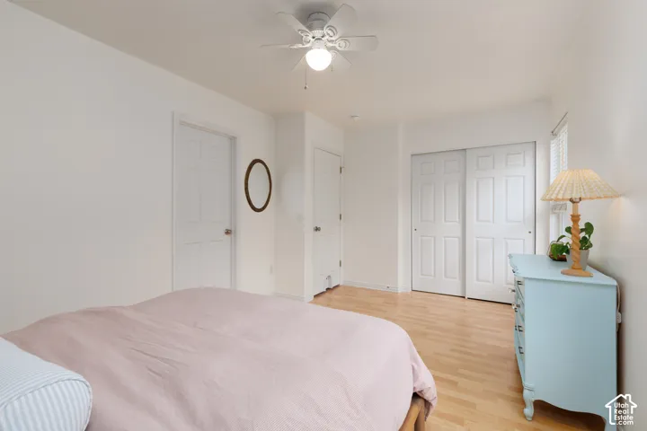 Wood-finish flooring, white paneled interior doors, and a ceiling-mounted light fixture with a multi-blade fan