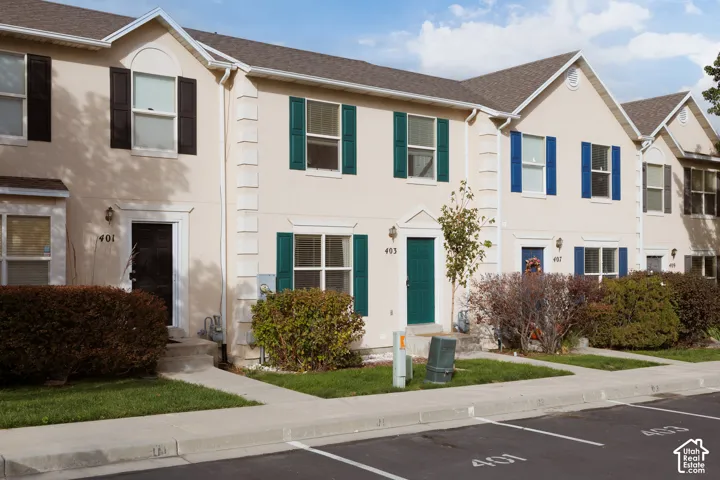 Multi-unit exterior featuring light-toned stucco siding, contrasting shutters, gabled rooflines, and decorative quoins