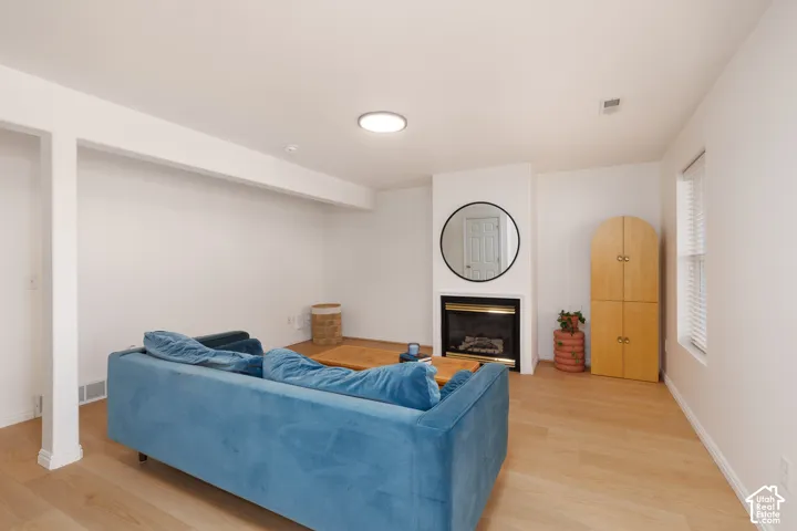 Fireplace with a black metal surround, wood-finish flooring, and recessed ceiling lighting