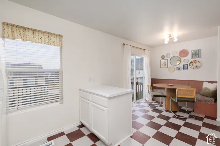 Checkered flooring, built-in corner bench seating with wainscoting, white base cabinet with solid-surface countertop, and sliding glass door