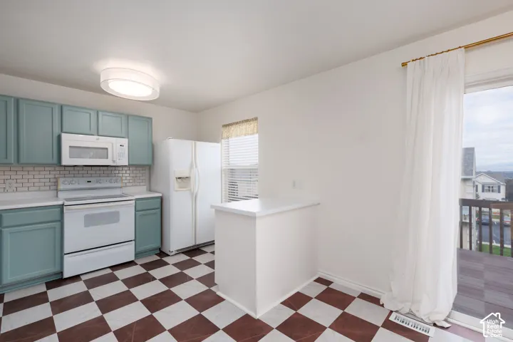 Kitchen featuring teal cabinetry, white countertops, subway tile backsplash, white appliances, and a checkered floor pattern