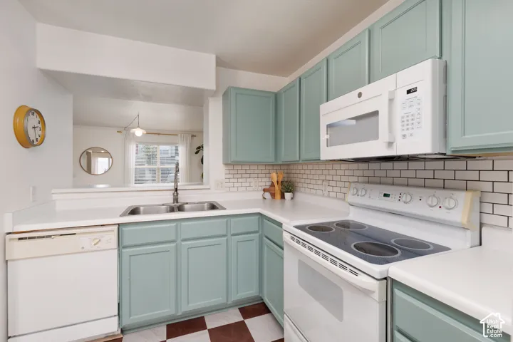 Kitchen featuring soft blue shaker-style cabinetry, white solid-surface countertops, a white subway tile backsplash, and a checkered-pattern floor