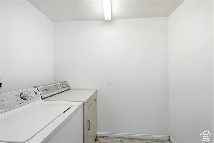 Enclosed utility area featuring white walls, resilient tile flooring, and ceiling-mounted linear lighting