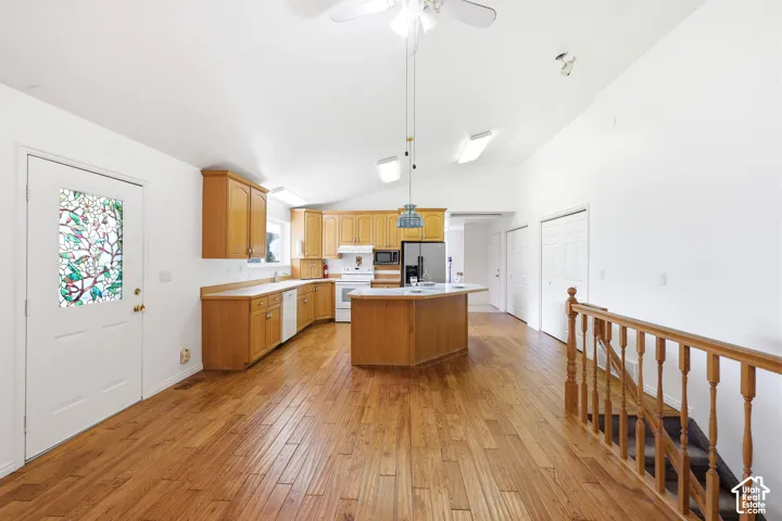 Vaulted ceilings, wood-finish flooring, custom cabinetry, center island, and exterior door featuring a decorative stained-glass inlay