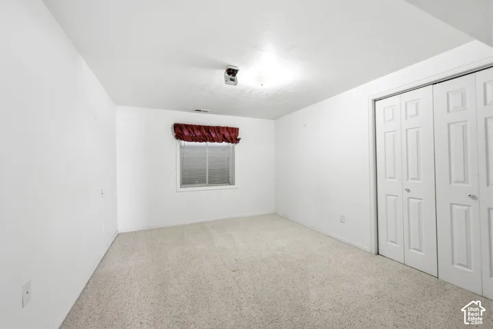 Neutral-toned carpeting, dual white paneled closet doors, and a single window with a white frame