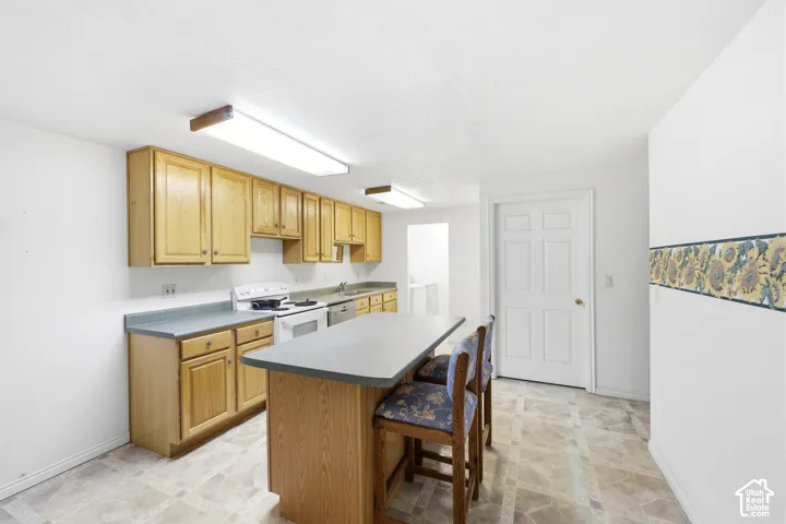 Kitchen featuring natural-finish wood cabinetry, solid-surface countertops, a center island, and patterned tile flooring