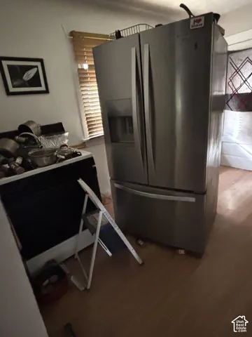 Stainless steel French-door refrigerator with exterior water and ice dispenser, paired with wood-finish flooring
