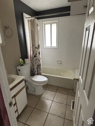 Bathroom featuring tile flooring, a tub-shower combination with white wall tile surround, a built-in vanity with integrated sink, and a single-pane window