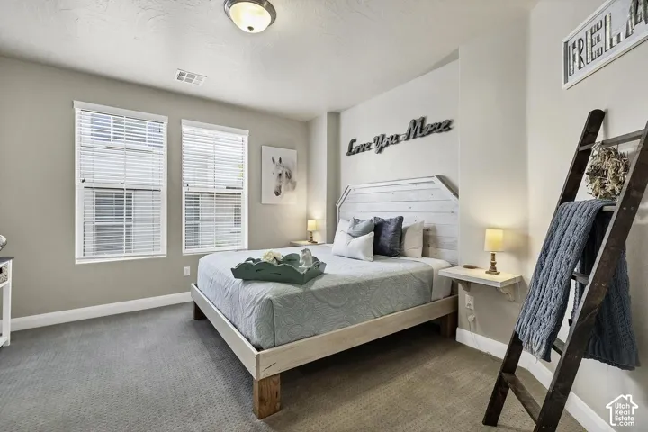 Neutral-toned room featuring dual windows with horizontal blinds, textured wall-to-wall carpeting, and wall-mounted floating shelves