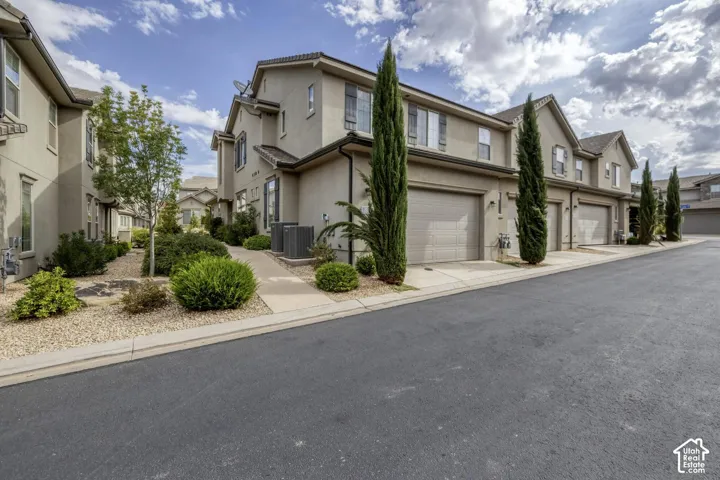 Multi-story stucco exterior with attached multi-car garages, asphalt-shingle roofing, and xeriscape landscaping
