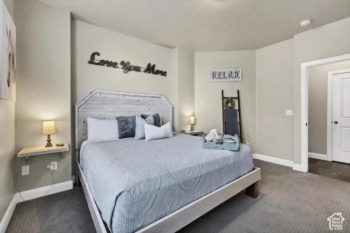 Neutral-toned bedroom featuring wall-to-wall carpeting, textured ceiling, and floating wall-mounted shelving
